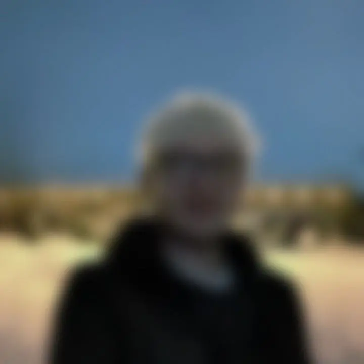 A blurry picture of Tom at night with a snowy ground and some lit up houses in the middleground